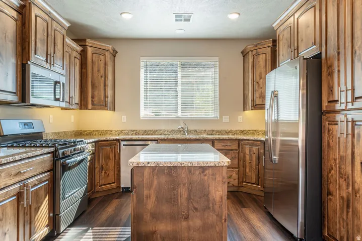 Kitchen featuring wood-finish cabinetry, stainless steel appliances, a central island, and recessed lighting