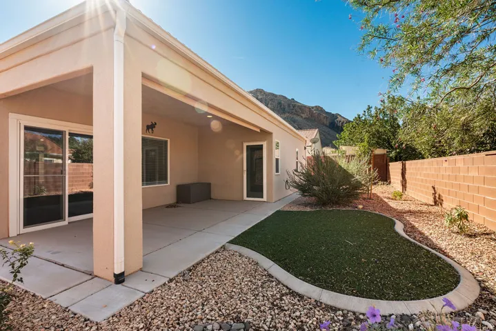 Covered patio with concrete flooring, sliding glass doors, and a low-maintenance artificial turf lawn