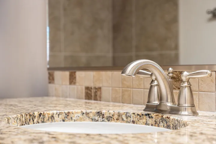 Granite-finish countertop with an undermount sink, brushed nickel faucet, and tiled backsplash