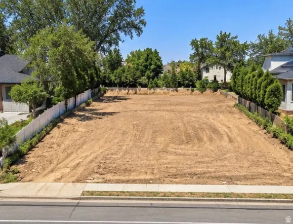 Expansive cleared lot featuring level ground, a concrete sidewalk, and established perimeter landscaping