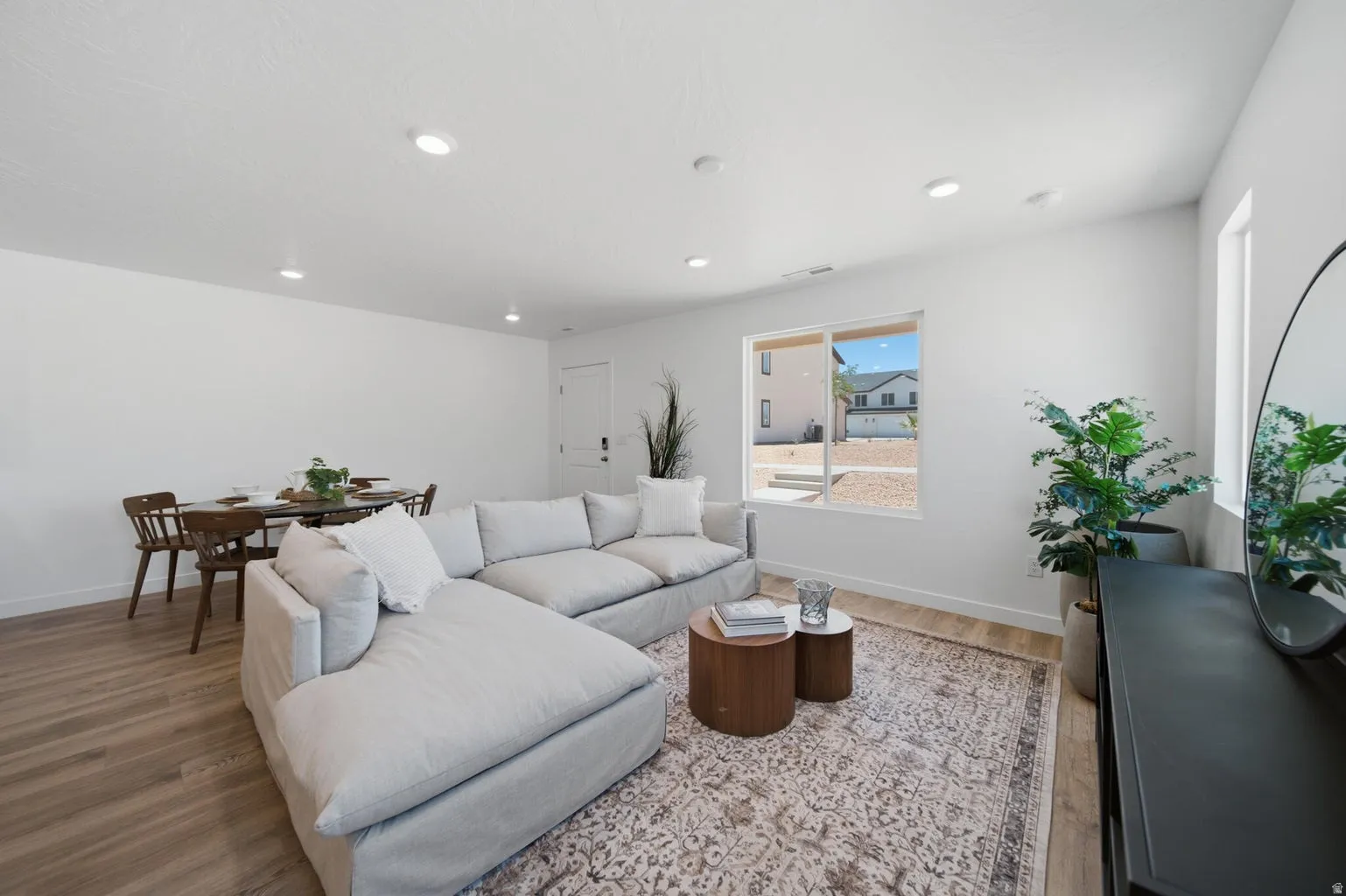 Spacious open-concept living area featuring wood-finish flooring, recessed lighting, and large windows