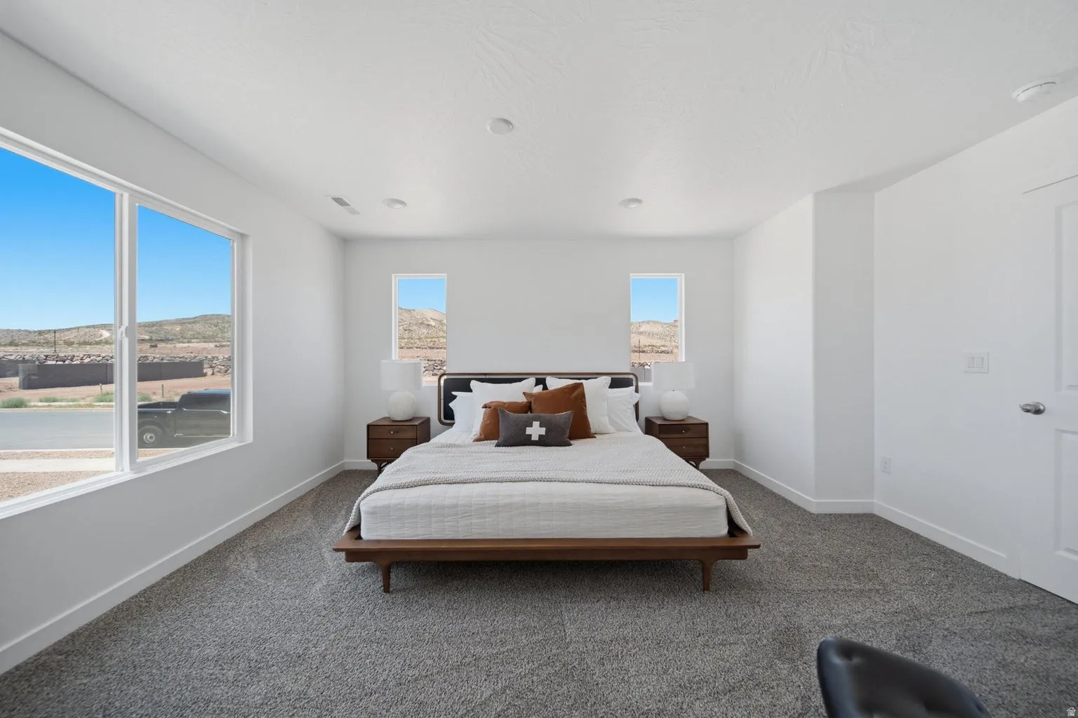 Recessed lighting, large windows, two smaller windows, and gray carpet flooring