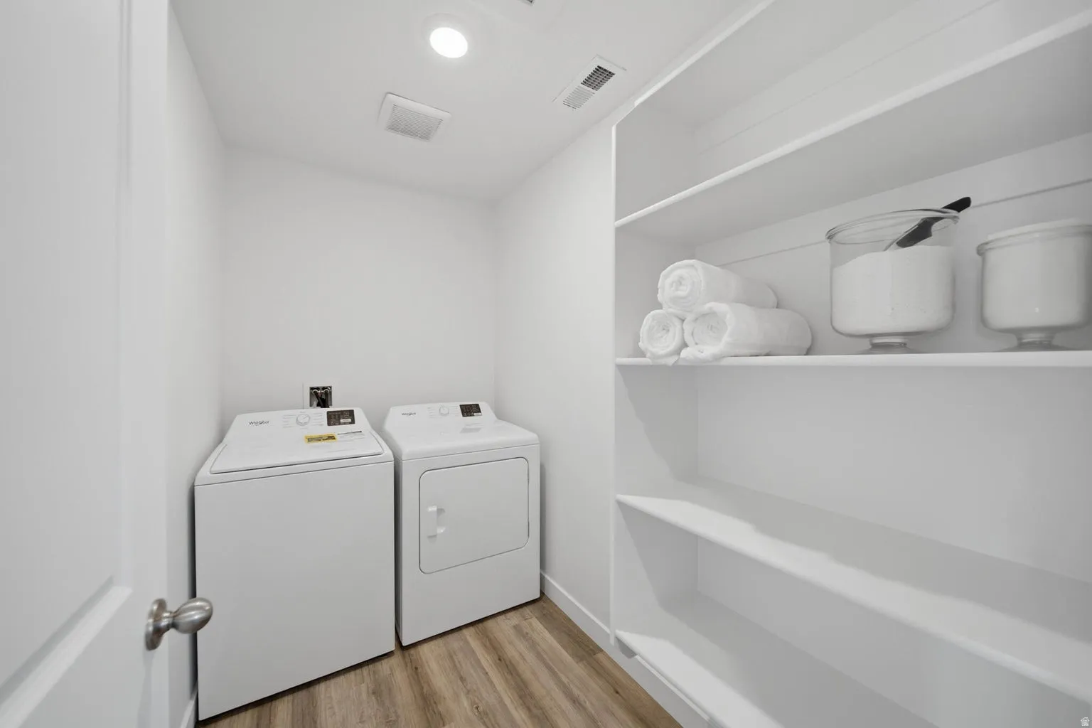 Laundry area with wood-finish flooring, recessed lighting, built-in shelving, and white walls