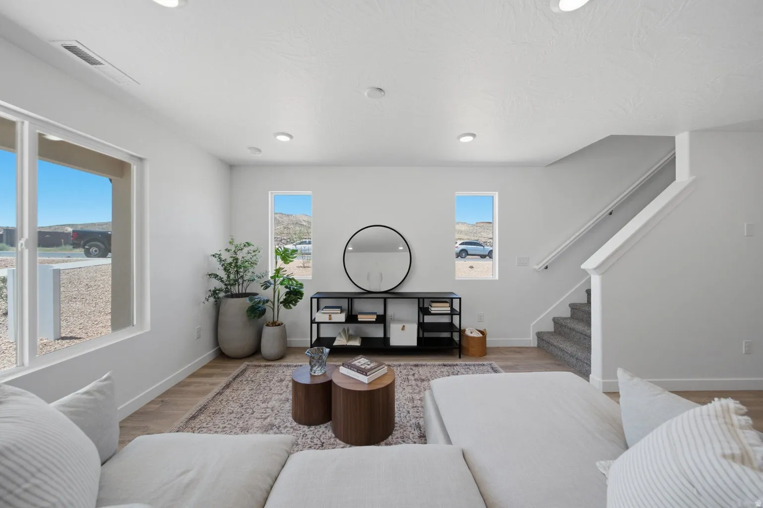 Recessed lighting, light wood-finish flooring, white walls, and a staircase with carpeted treads