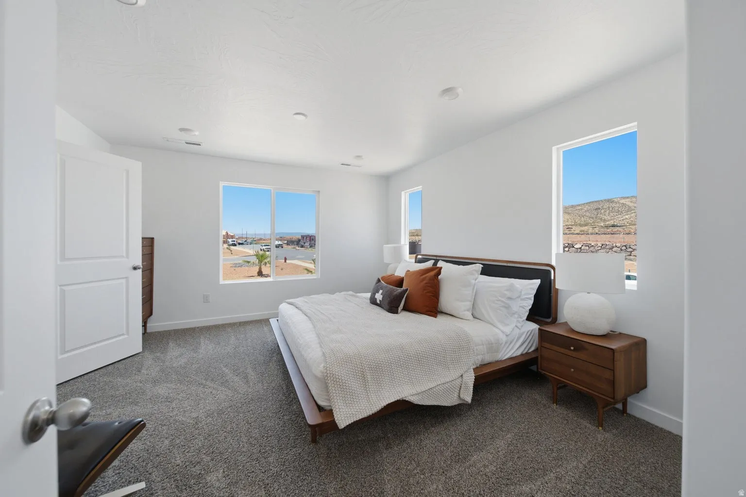 Recessed lighting illuminates the carpeted room, featuring multiple windows