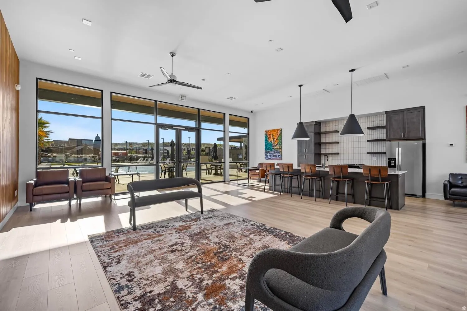 Open-concept common area featuring wood-finish flooring, a full kitchen with dark cabinetry and stainless steel appliances, and a built-in bar with pendant lighting