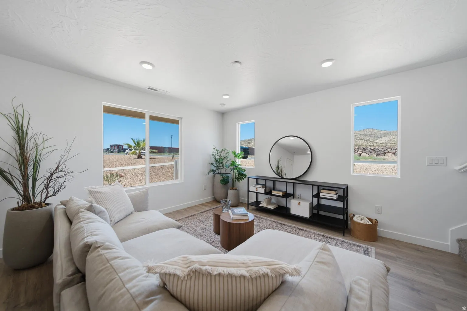 Recessed ceiling lighting, multiple windows, wood-finish flooring, and crisp white walls