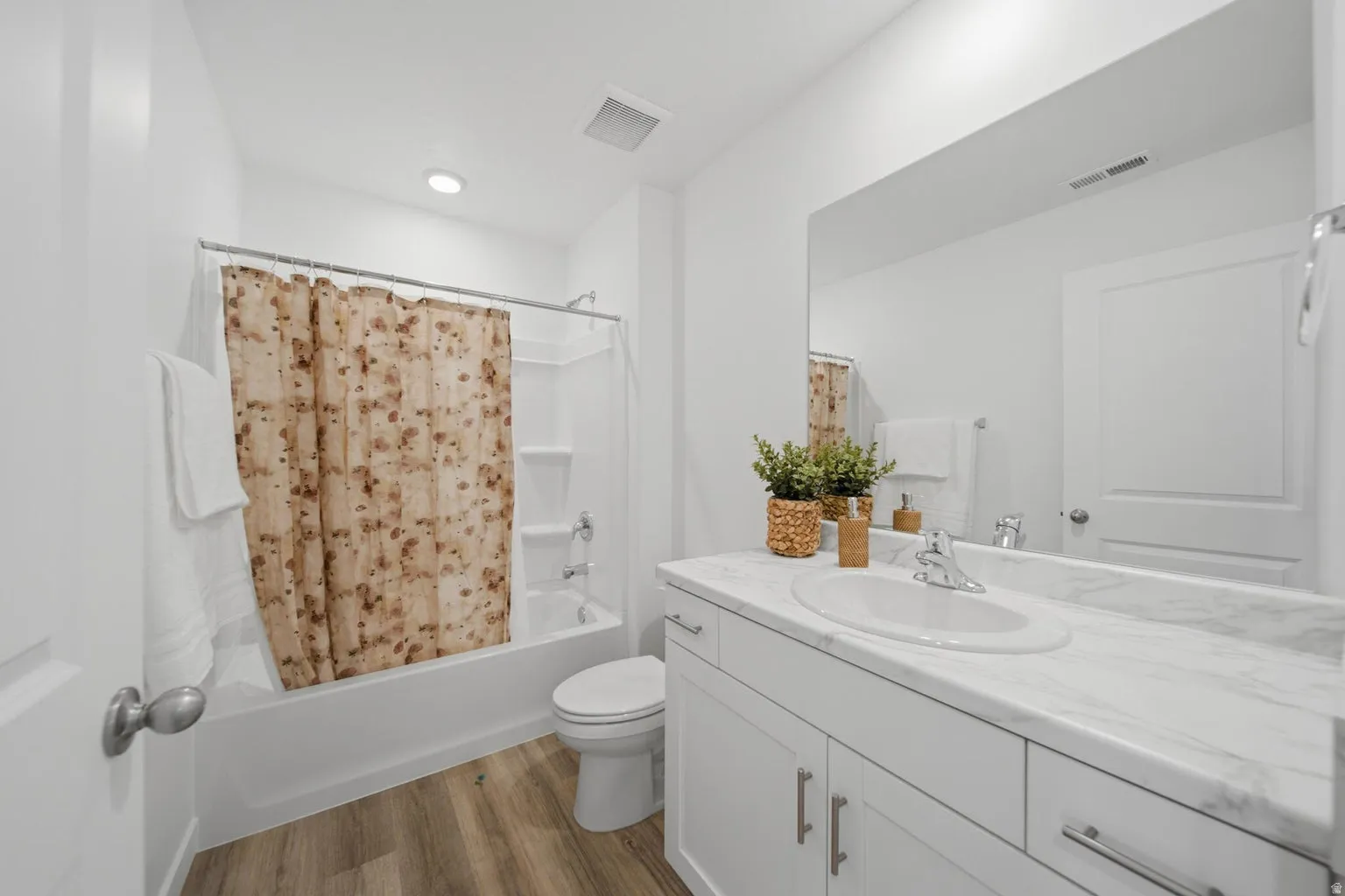 White bathroom vanity with an integrated sink, polished chrome faucet, and expansive mirror