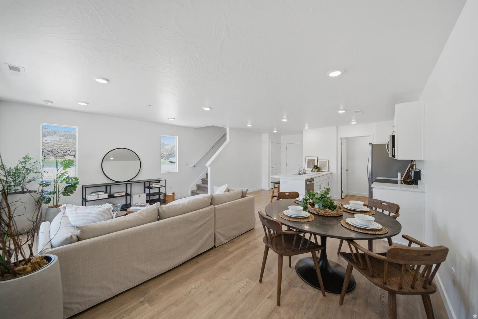 Open-concept living space featuring wood-finish flooring, recessed lighting, and multiple windows