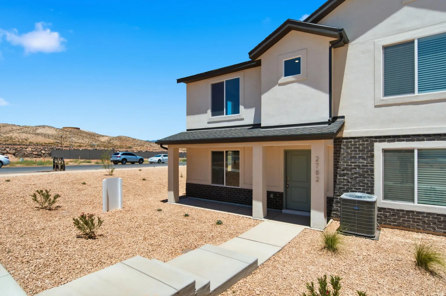 Stucco exterior with brick veneer accents, covered entry, and a concrete pathway
