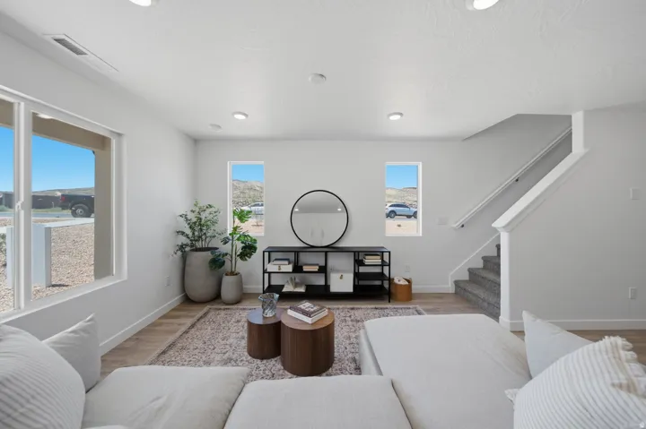 Recessed lighting, light wood-finish flooring, white walls, and a staircase with carpeted treads
