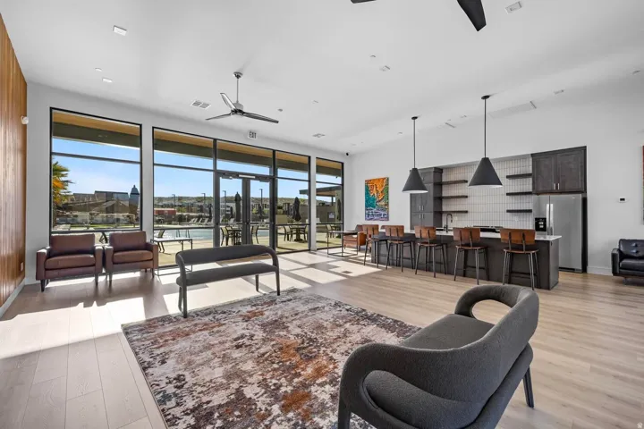 Open-concept common area featuring wood-finish flooring, a full kitchen with dark cabinetry and stainless steel appliances, and a built-in bar with pendant lighting