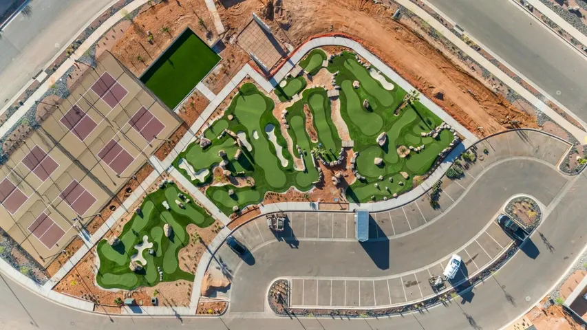 Recreational area featuring multiple pickleball courts, a miniature golf course with varied terrain, artificial turf putting green, and a parking area