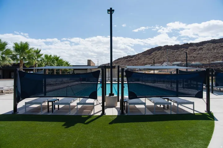 Swimming pool with a surrounding artificial turf area, shade structures, and concrete decking