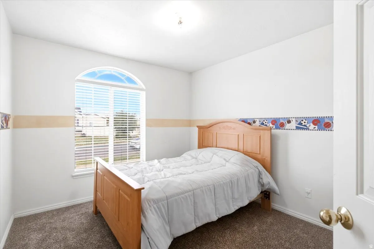 Arched window with blinds, carpeted flooring, and a ceiling-mounted light fixture