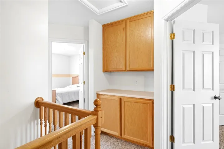 Built-in cabinetry with a light-toned countertop, wood-finish railing, and white paneled doors