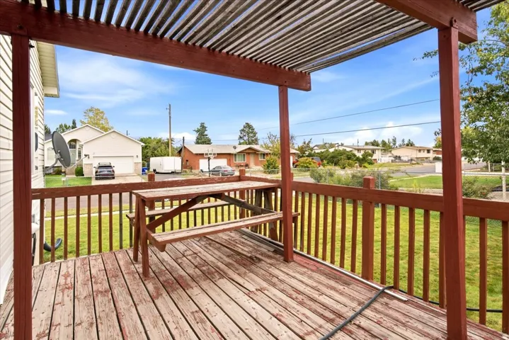 Outdoor deck with wood railings, a slatted pergola, and wood plank flooring