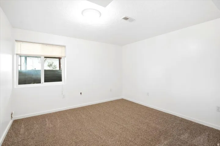 Recessed window, neutral wall paint, ceiling-mounted light fixture, brown carpet, and white trim