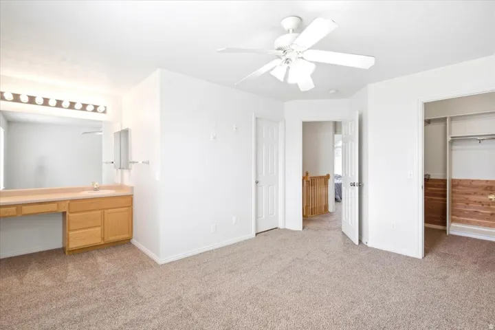 Light-colored carpeting with a built-in vanity featuring a single sink and light wood cabinetry