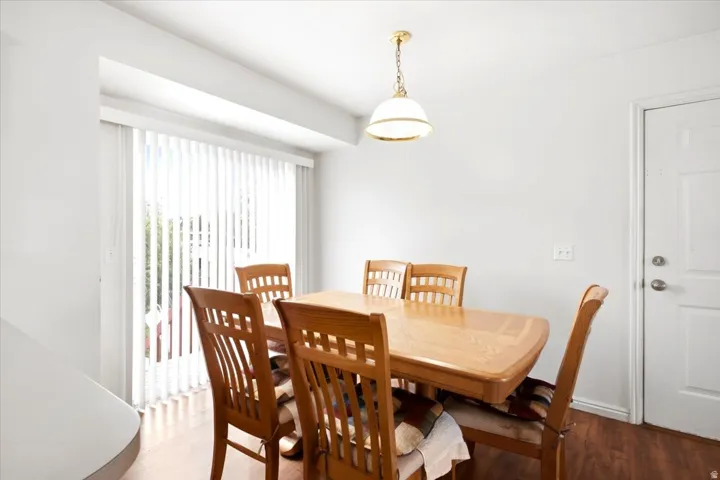 Recessed wall featuring a sliding glass door with vertical blinds, wood-finish flooring, and a ceiling-mounted light fixture