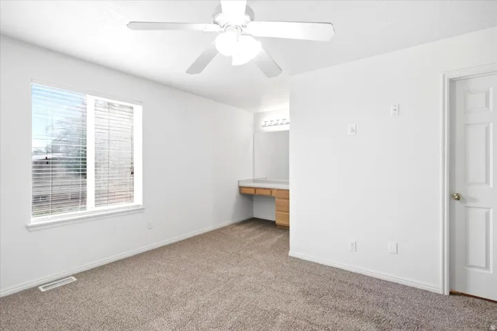 Wall-to-wall carpeting, ceiling fan, and window with horizontal blinds