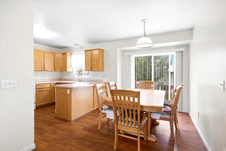 Kitchen featuring wood-finish flooring, light wood cabinetry, a center island, and a sink with a window overhead