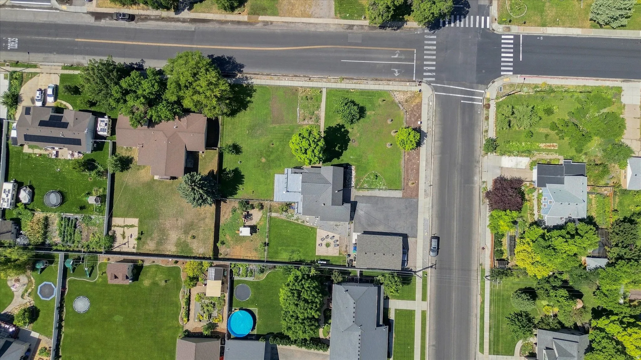 Corner lot property with a detached accessory structure, mature trees, and an established lawn