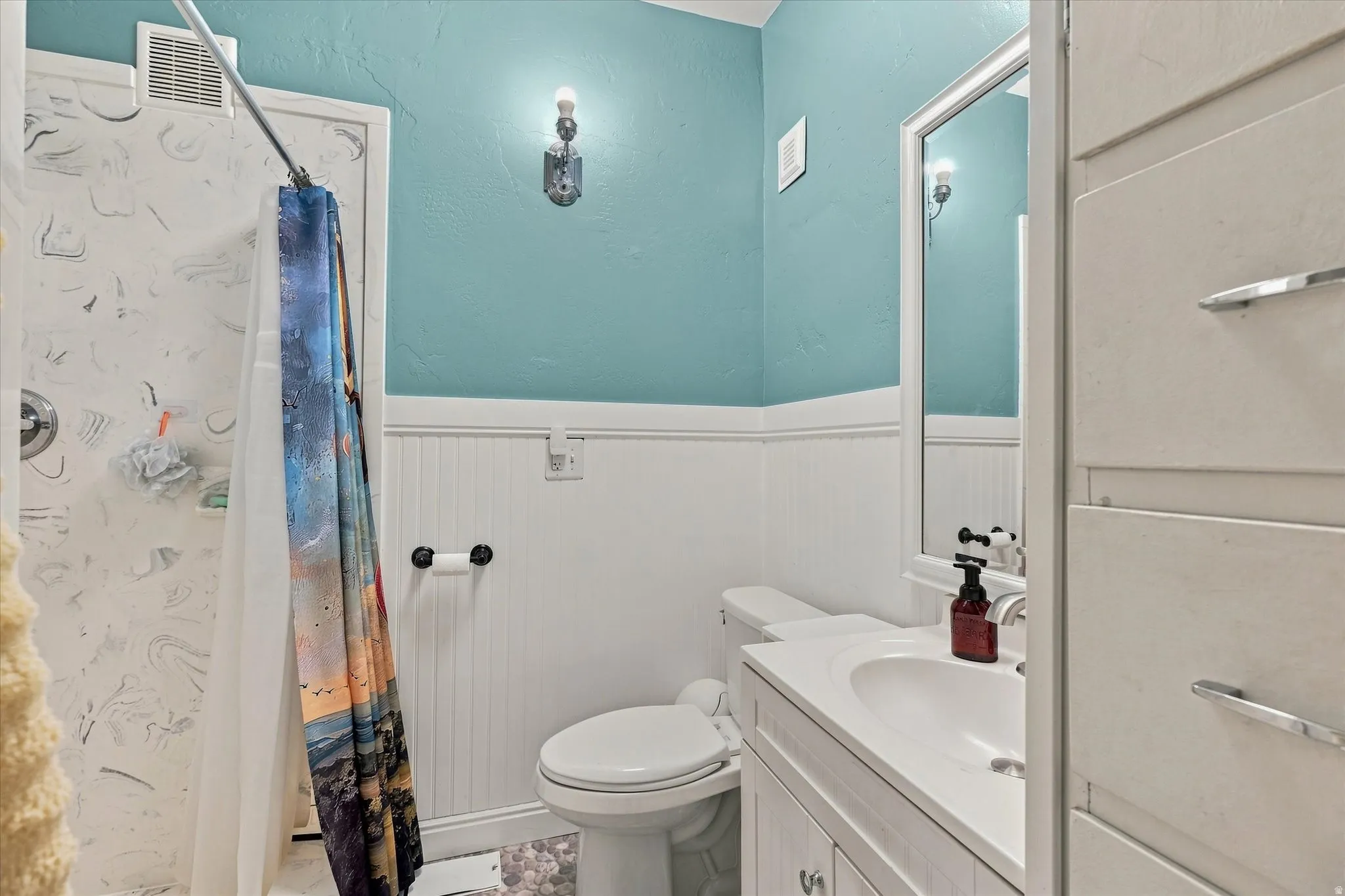 White vanity with integrated sink, framed mirror, and beadboard wainscoting