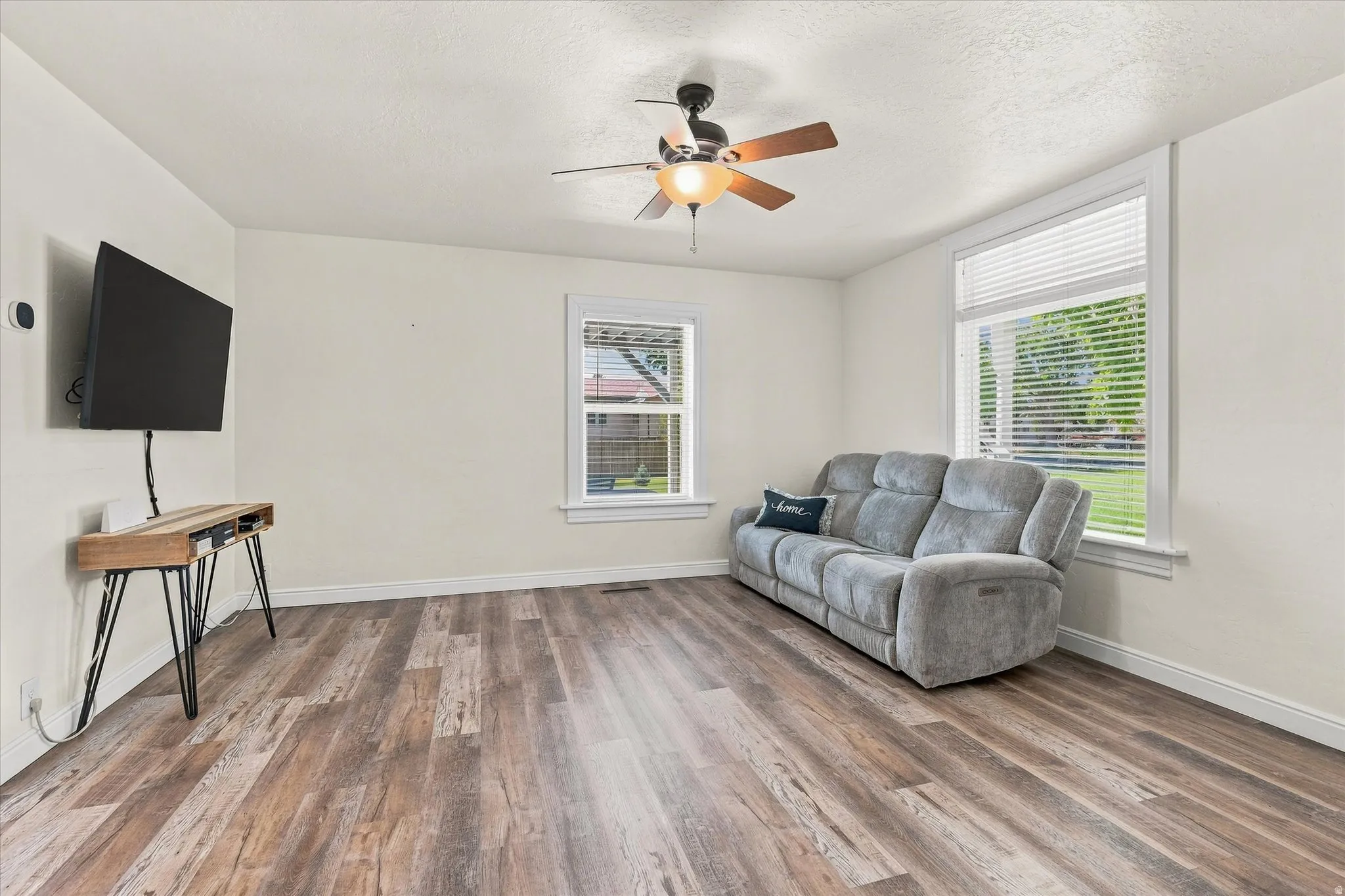 Wood-finish flooring throughout, ceiling fan with integrated lighting, and white window blinds