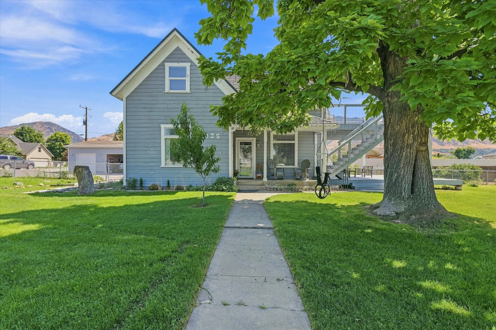 Light blue siding, white trim, and a concrete pathway