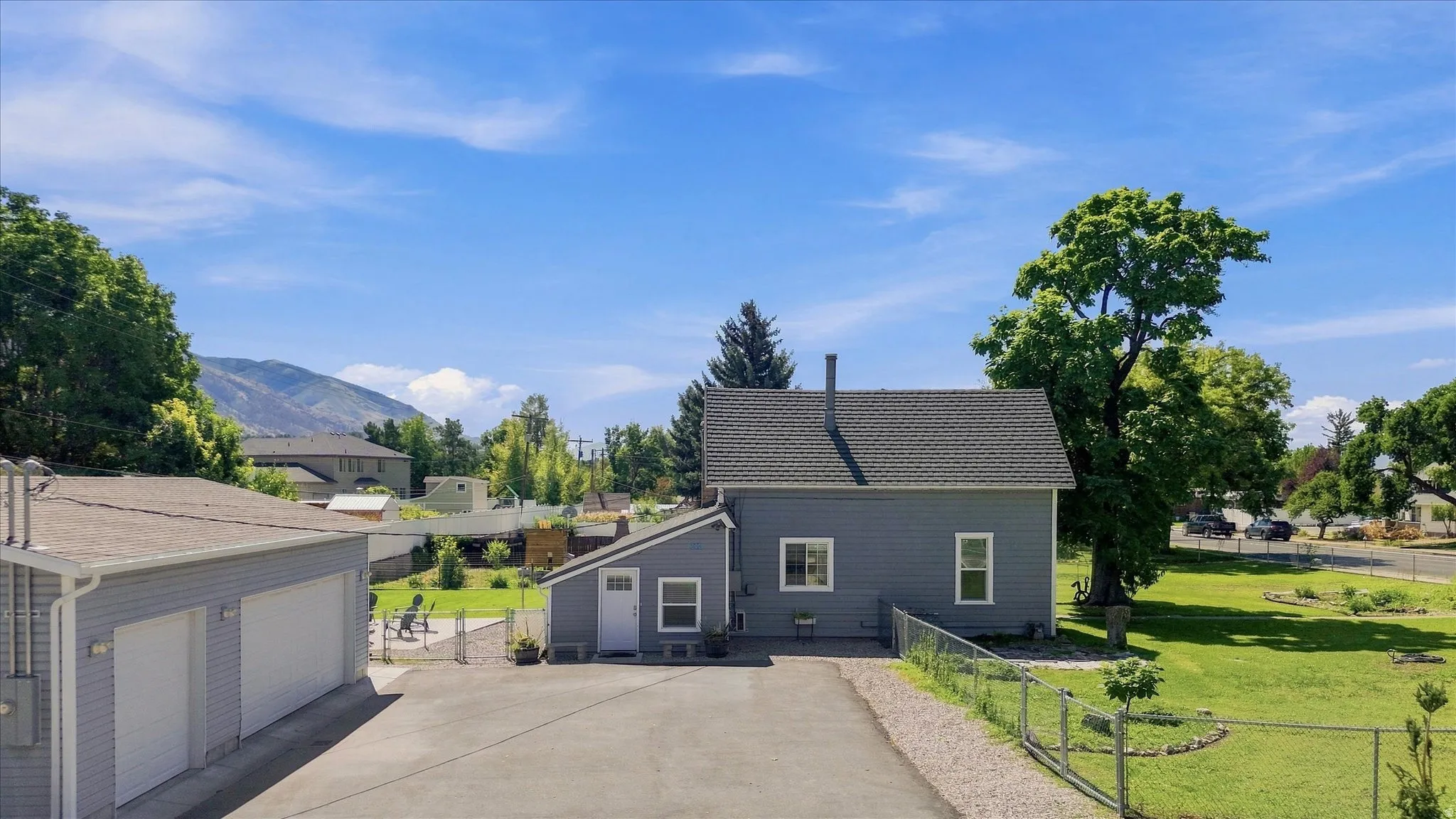 Two-car garage with white doors, gravel driveway, and a fenced yard