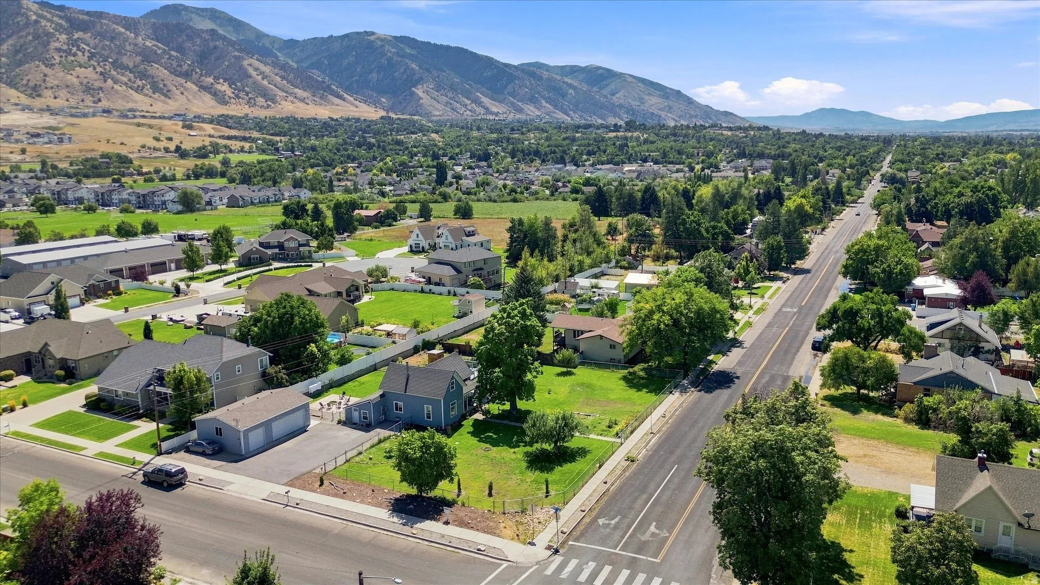 Expansive mountain backdrop with a wide residential street, mature trees, and surrounding green spaces