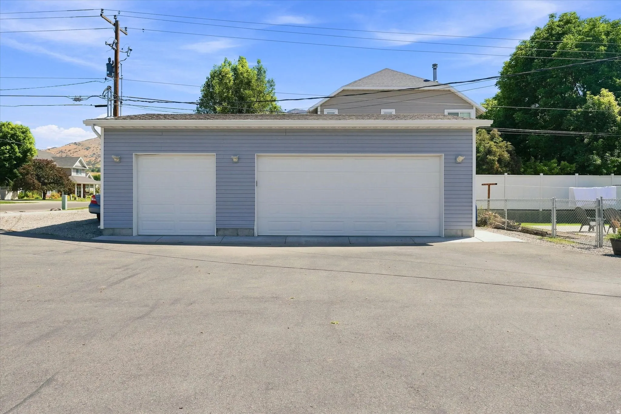 Two-car garage with light blue siding and a single overhead door, featuring exterior wall sconces and a concrete foundation