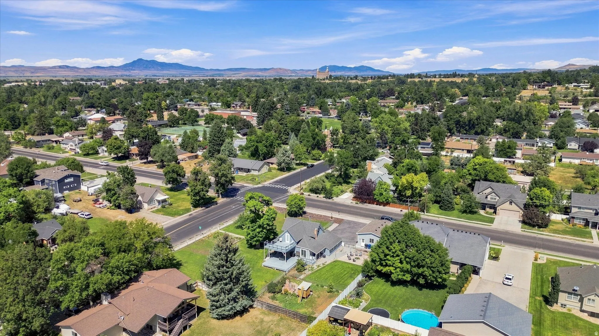 Expansive residential neighborhood featuring established trees, paved streets, and distant mountain ranges