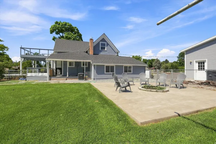 Expansive green lawn, multi-level deck, concrete patio, and separate structure with a white door