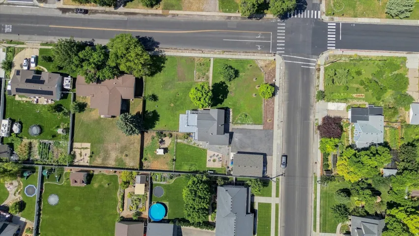 Corner lot property with a detached accessory structure, mature trees, and an established lawn