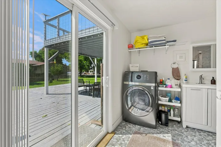 Laundry area with hexagonal floor tiles, white wall-mounted shelving, and a vanity with an integrated sink