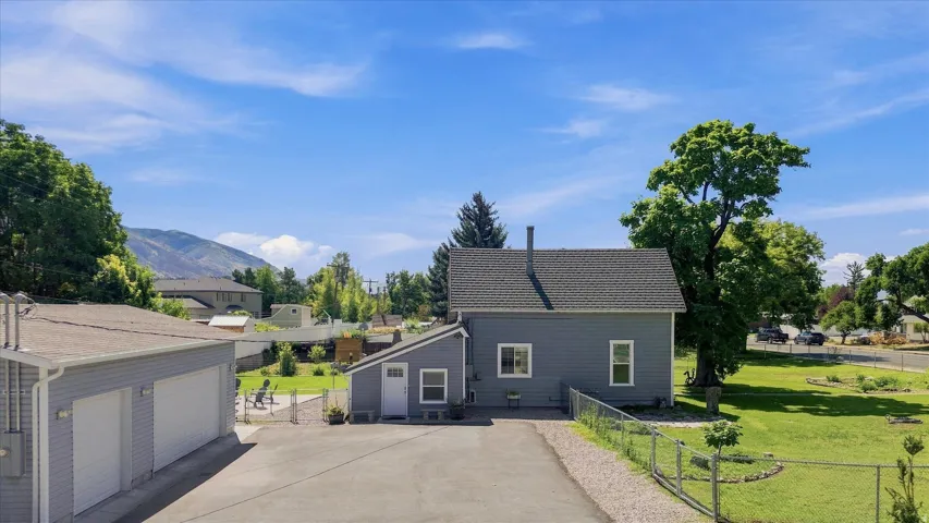 Two-car garage with white doors, gravel driveway, and a fenced yard