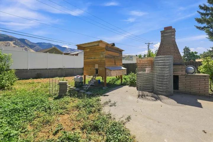 Backyard featuring a brick outdoor fireplace, a raised wooden structure, and mountain scenery