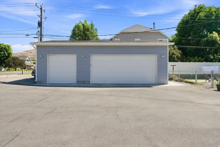 Two-car garage with light blue siding and a single overhead door, featuring exterior wall sconces and a concrete foundation