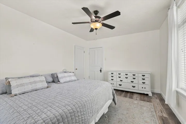 Ceiling fan with integrated lighting, wood-finish flooring, white window blinds, and white interior doors