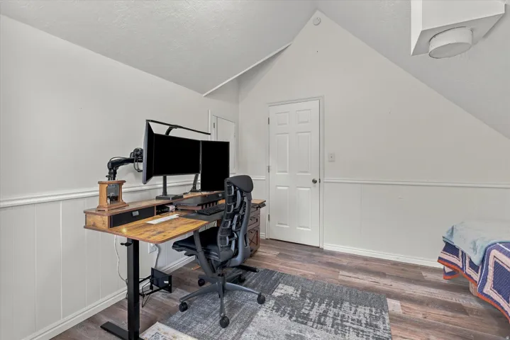 Angled ceiling, wood-finish flooring, white paneling, white door, surface-mounted light fixture