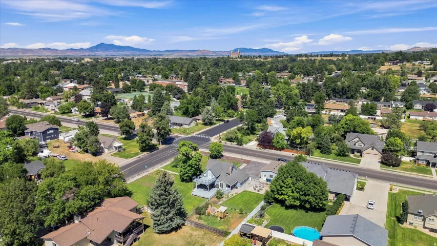 Expansive residential neighborhood featuring established trees, paved streets, and distant mountain ranges