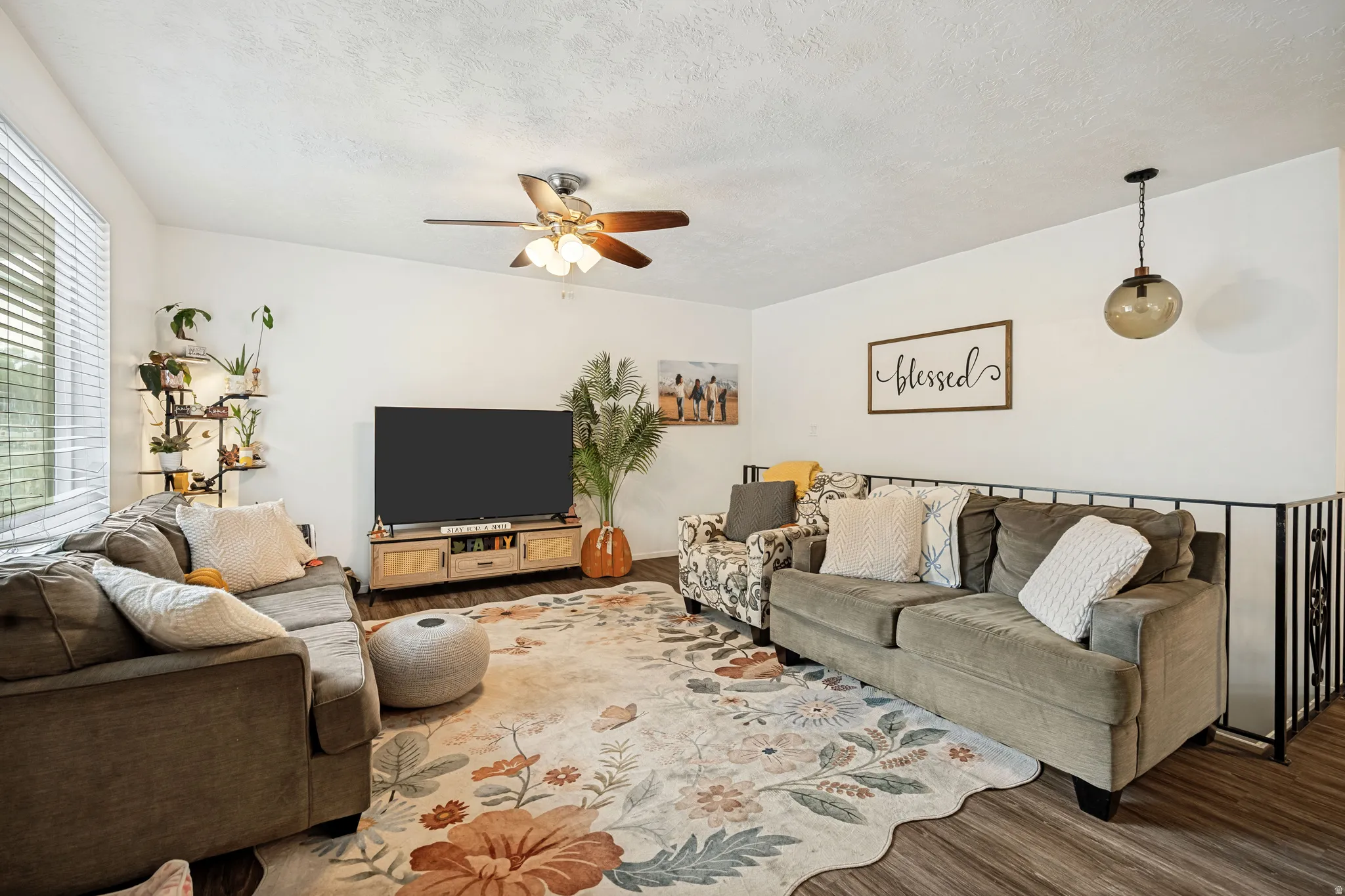6711 - Living area featuring wood-finish flooring, a ceiling fan, and a built-in metal railing
