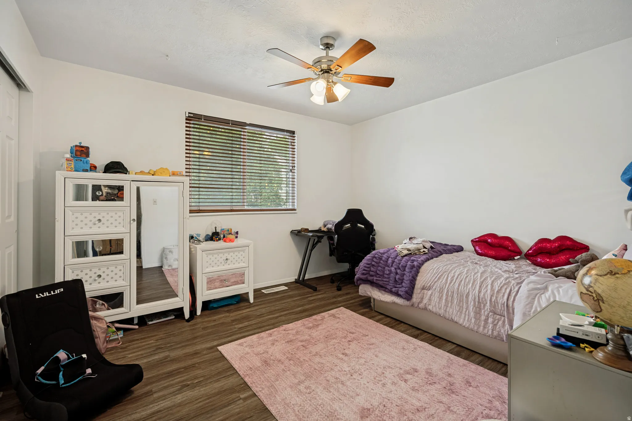 6711 - Main level bedroom 2. Wood-finish flooring, ceiling fan with integrated lighting, white walls, and window with blinds