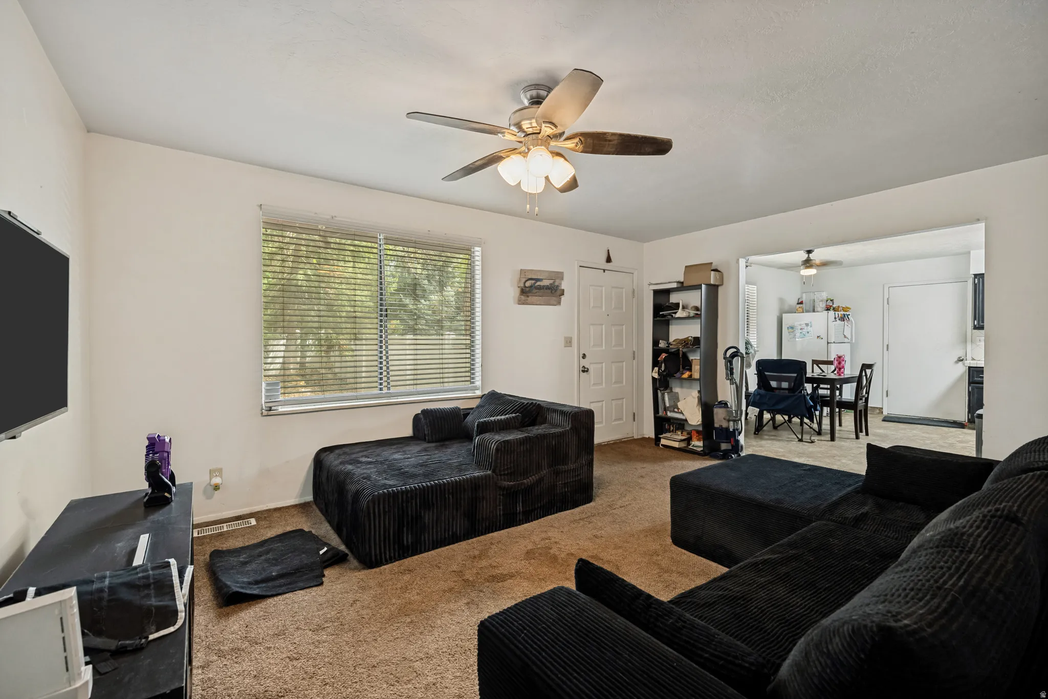 6709 - Main level living room. Carpeted living area with a ceiling fan, a window with horizontal blinds, and a doorway opening to an additional room