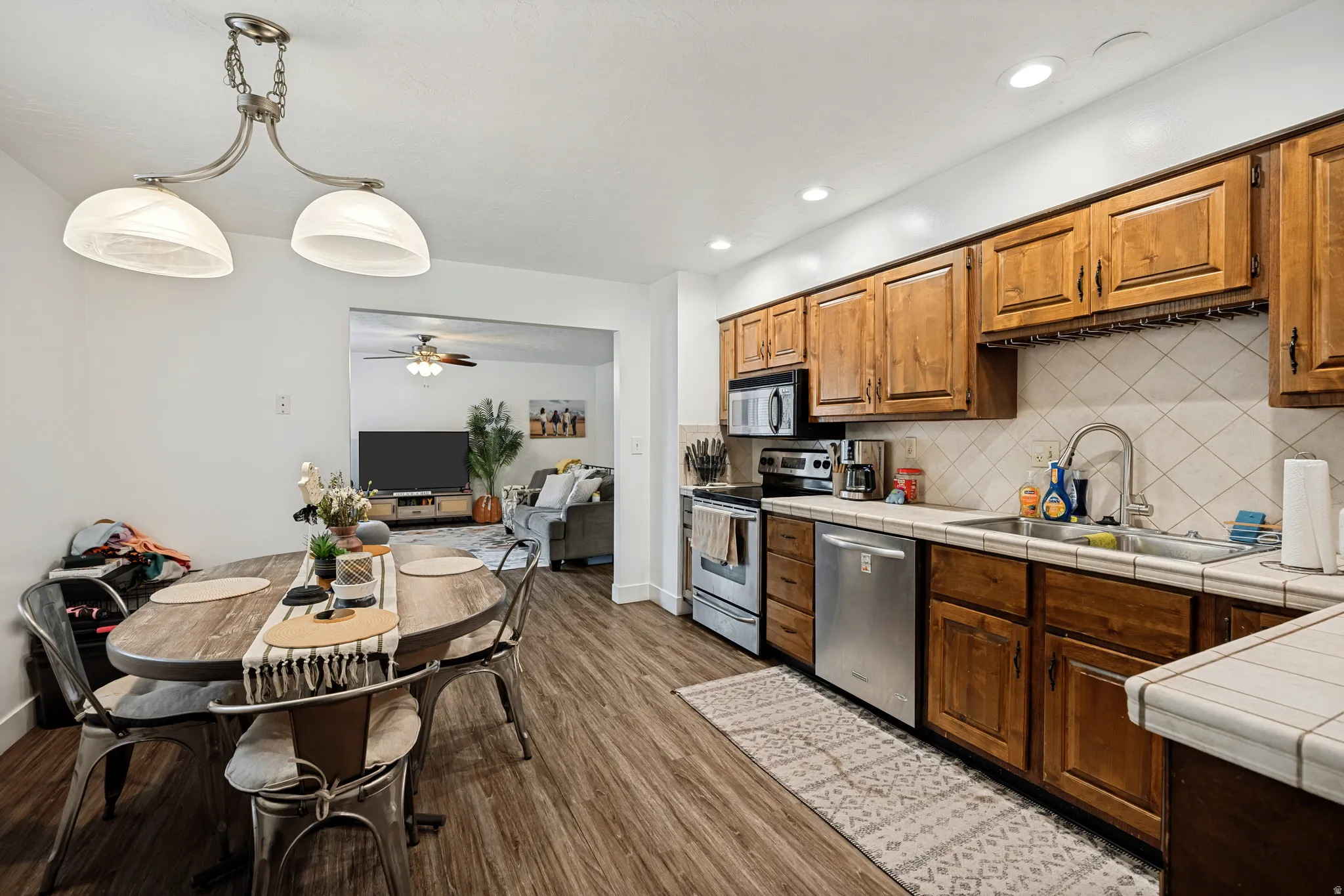 6711 - Wood-finish flooring, wood cabinetry, stainless steel appliances, recessed lighting, and a tile backsplash