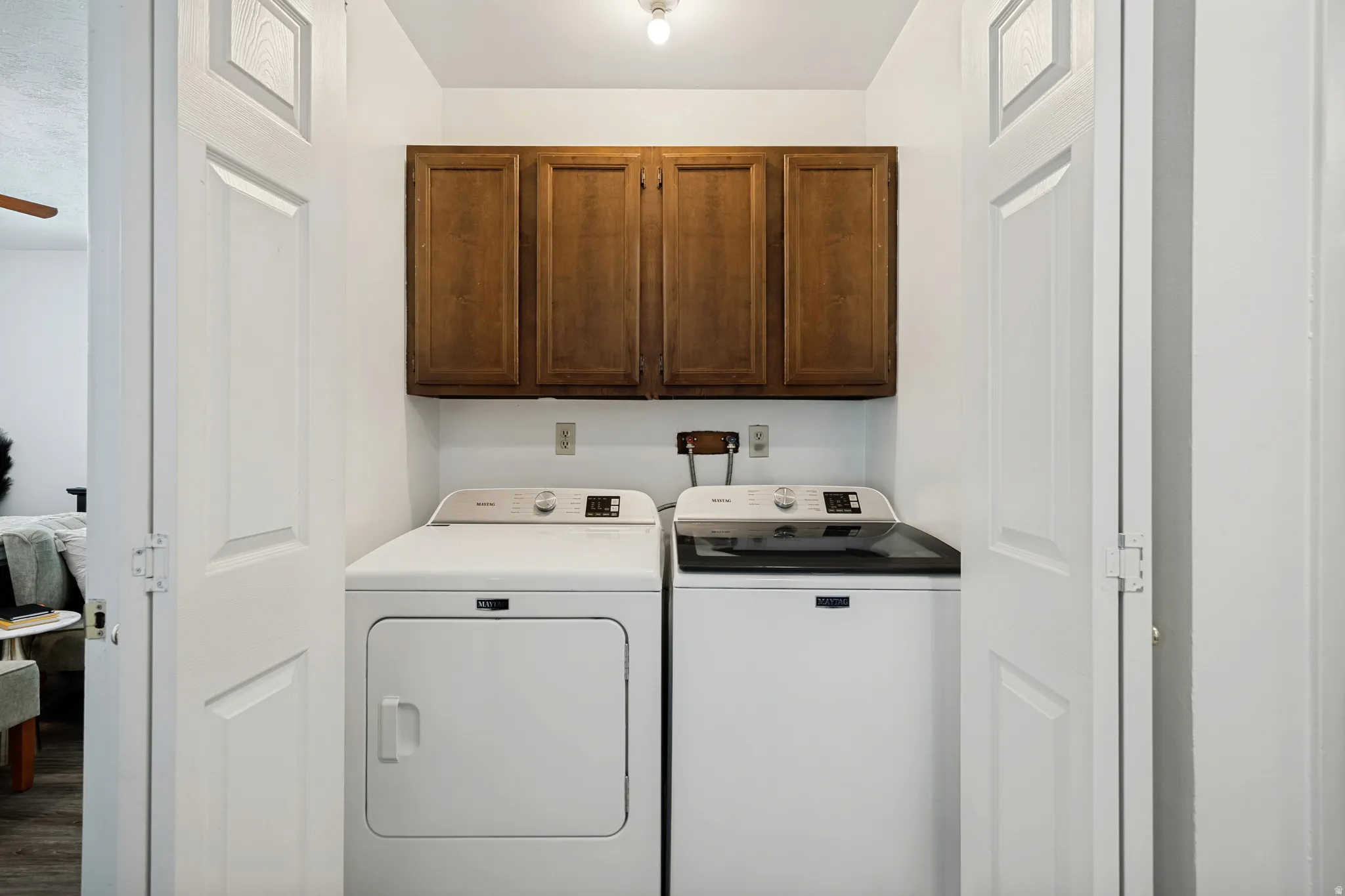 6711 - main level. Dedicated laundry area featuring a white top-load washing machine, white front-load dryer, and wood-finish upper cabinetry
