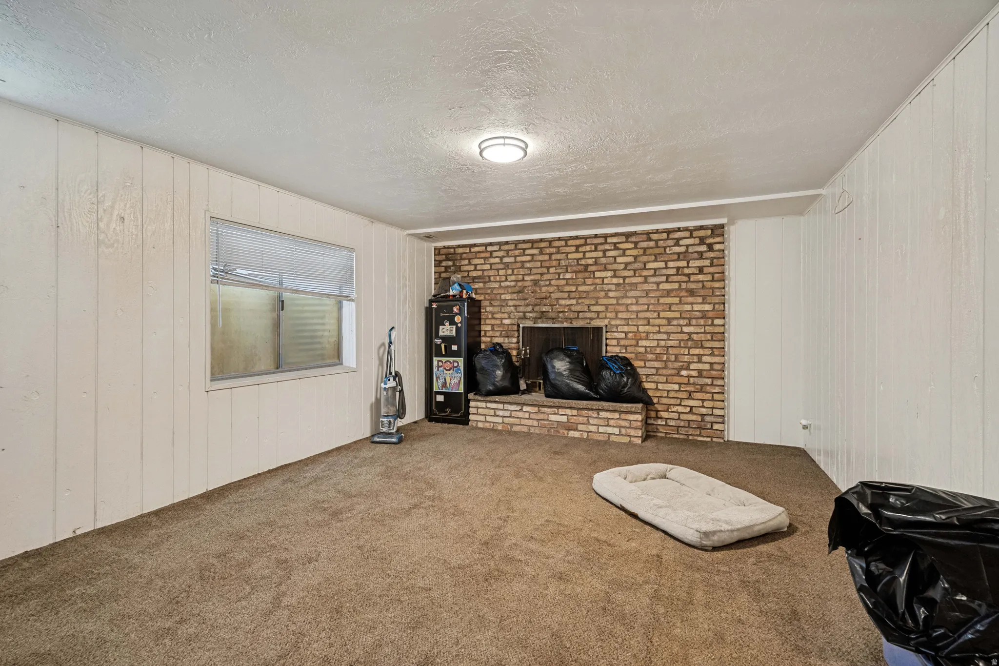 6709 - Basement Living Room. Brown brick fireplace with a raised hearth, white vertical paneling, and a flush-mount ceiling light