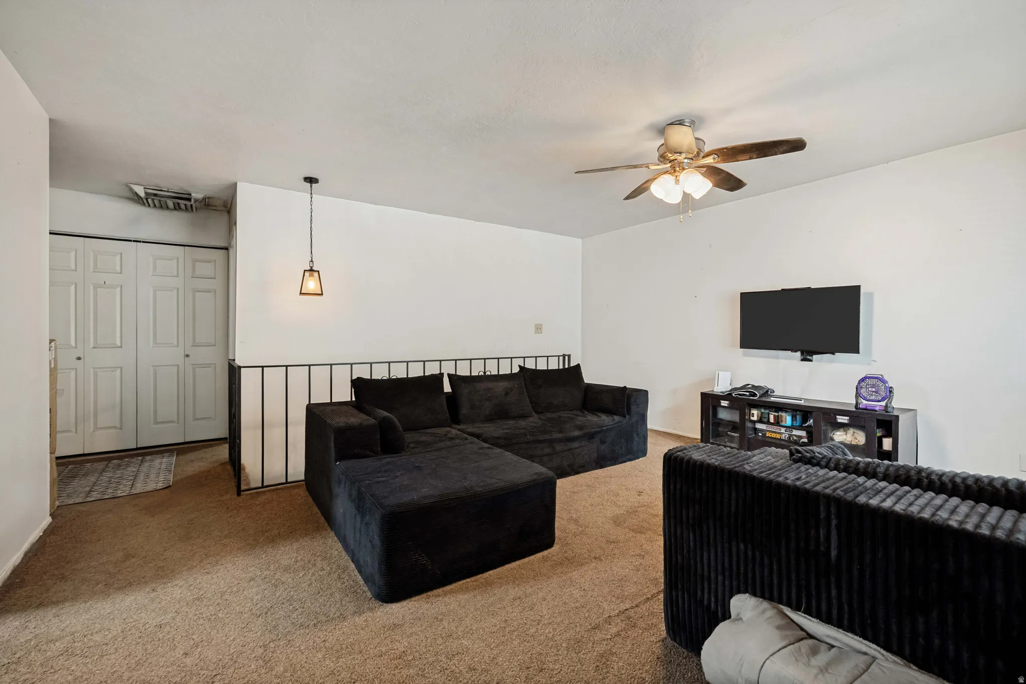 6709 -Main level living room. Neutral wall finishes, carpet flooring, a ceiling fan with integrated lighting, and a pendant light fixture